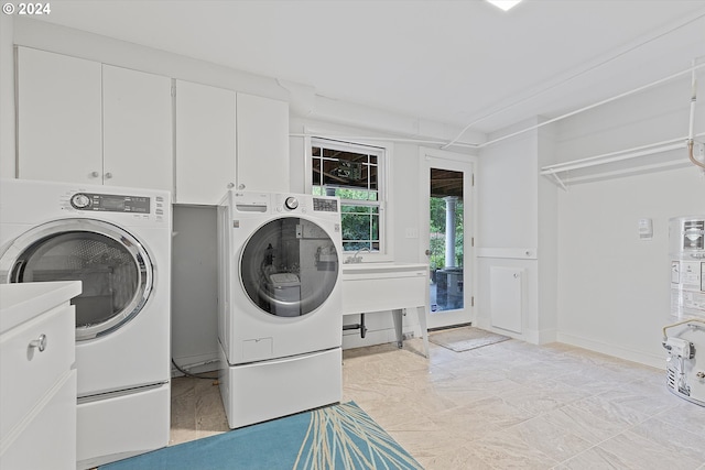 clothes washing area with washing machine and dryer and cabinet space