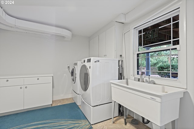 washroom with cabinet space, a sink, and washing machine and clothes dryer