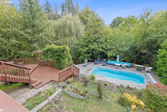 outdoor pool featuring a patio area, a wooden deck, and a vegetable garden