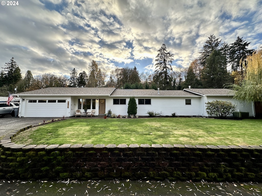 ranch-style home with cooling unit, a garage, and a front lawn