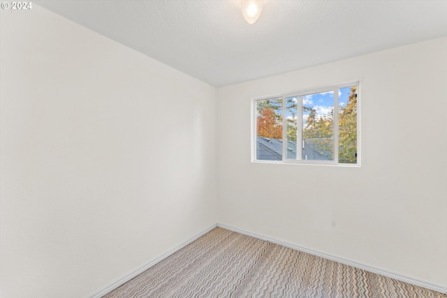 carpeted empty room featuring a textured ceiling