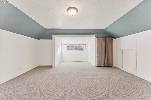 bonus room with a textured ceiling, light carpet, and lofted ceiling