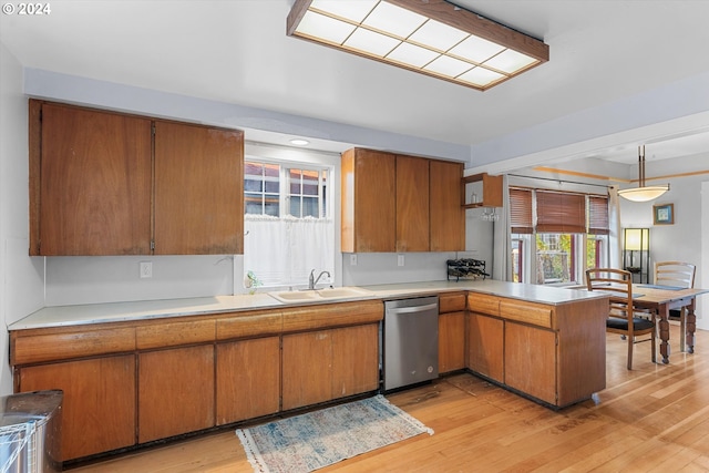 kitchen with dishwasher, sink, hanging light fixtures, and light wood-type flooring