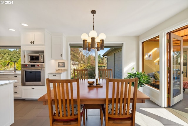 tiled dining room featuring an inviting chandelier and sink