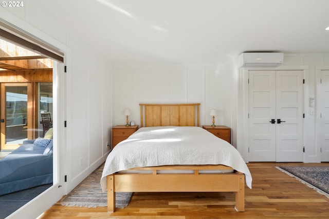 bedroom featuring access to exterior, a wall unit AC, and hardwood / wood-style flooring