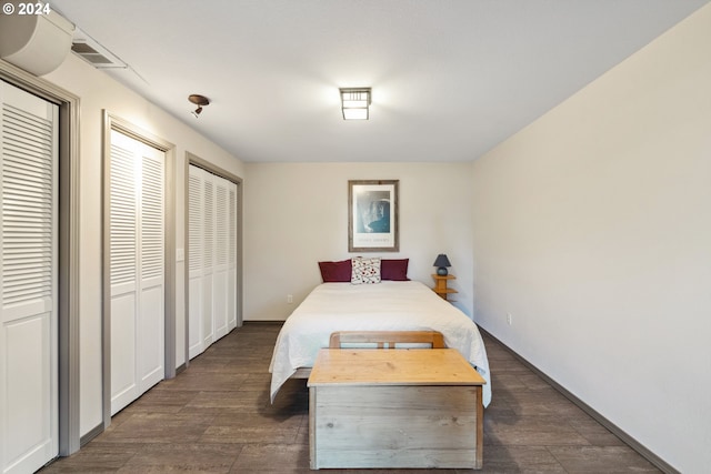 bedroom featuring dark wood-type flooring and multiple closets