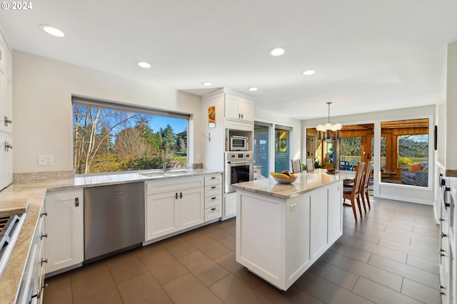 kitchen with stainless steel appliances, white cabinets, decorative light fixtures, and sink