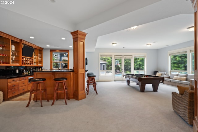 interior space with light carpet, billiards, decorative columns, and bar area