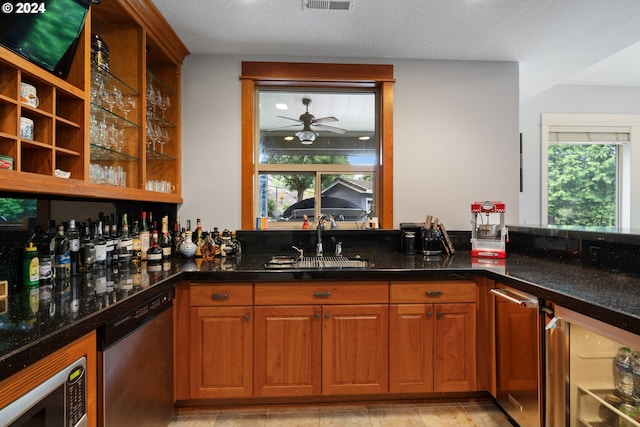 bar with a healthy amount of sunlight, appliances with stainless steel finishes, sink, and dark stone counters