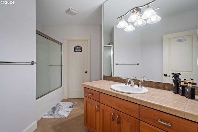 bathroom featuring vanity, bath / shower combo with glass door, and tile patterned floors