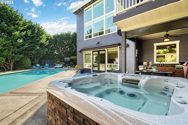 view of swimming pool with ceiling fan and a hot tub