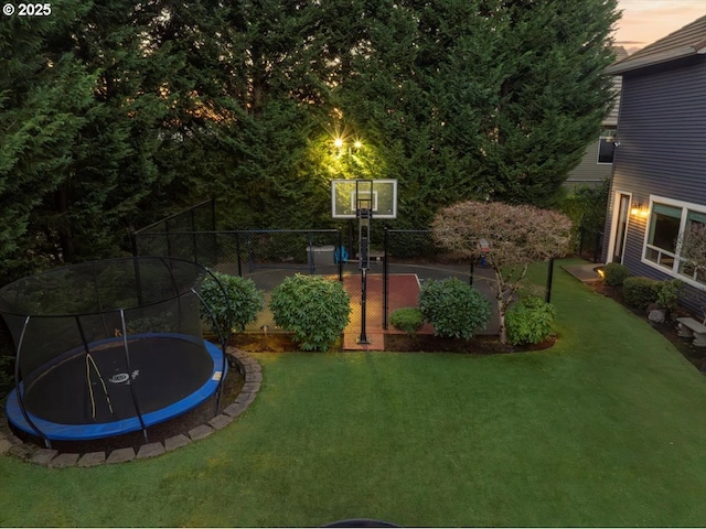 view of sport court with a yard and a trampoline