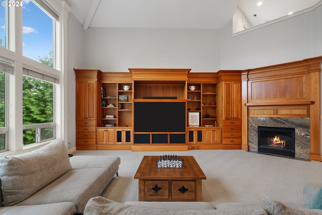 living room featuring a premium fireplace, a healthy amount of sunlight, light carpet, and high vaulted ceiling