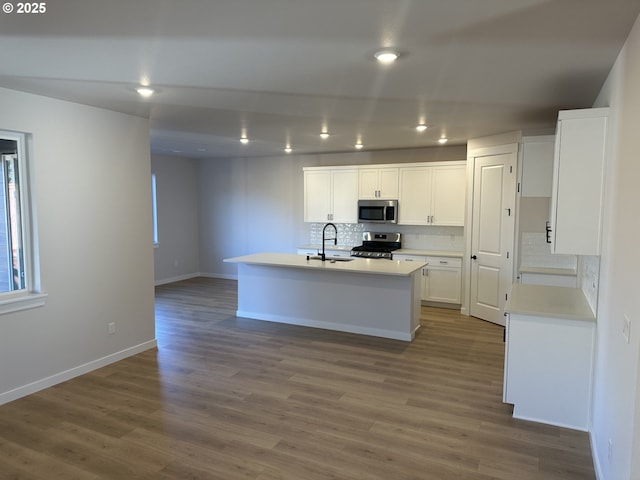 kitchen featuring a center island with sink, sink, white cabinetry, and stainless steel appliances