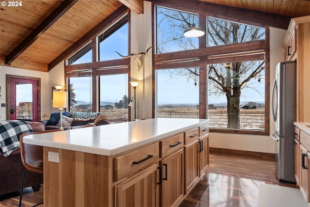 kitchen featuring a healthy amount of sunlight, beamed ceiling, a center island, dark hardwood / wood-style floors, and stainless steel refrigerator