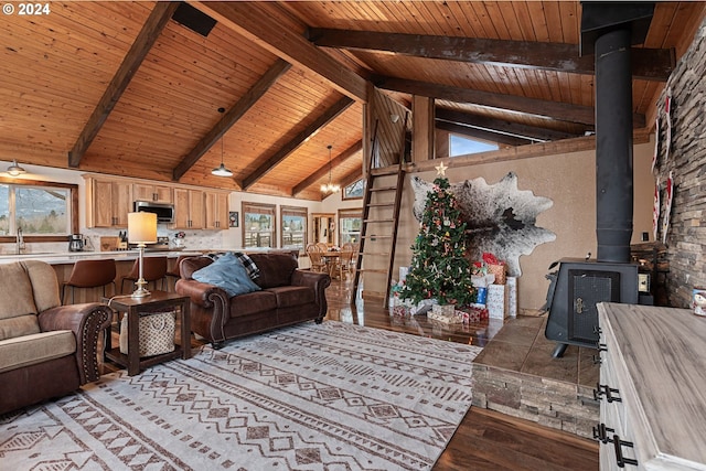 living room with a wood stove, wooden ceiling, sink, light wood-type flooring, and beamed ceiling