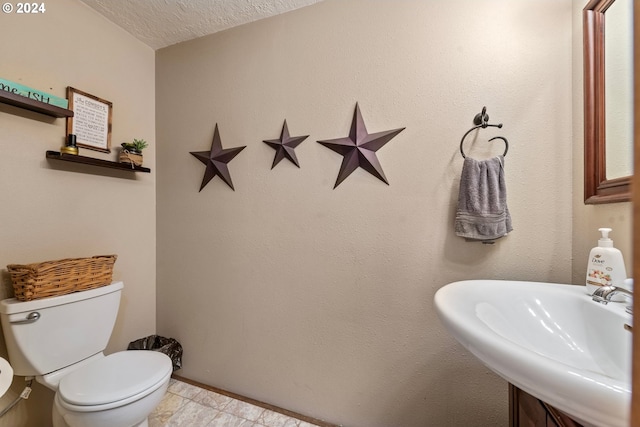 bathroom with toilet, sink, and a textured ceiling