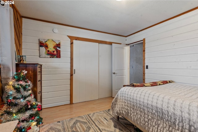 bedroom featuring light wood-type flooring, a textured ceiling, and wooden walls