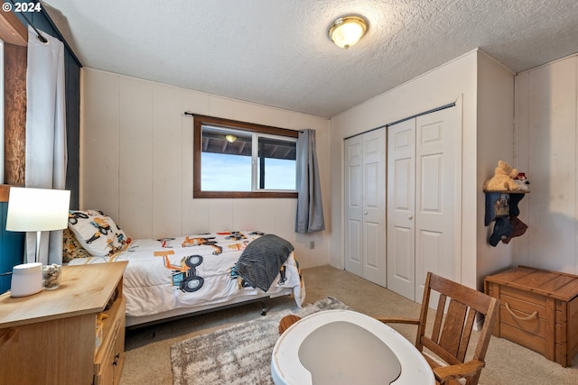 carpeted bedroom featuring a textured ceiling and a closet