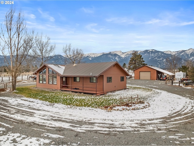 view of snowy exterior with an outbuilding, a mountain view, and a garage