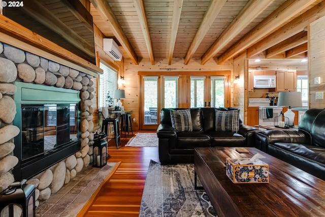 living room featuring a wall mounted air conditioner, wooden walls, wood-type flooring, beam ceiling, and a fireplace