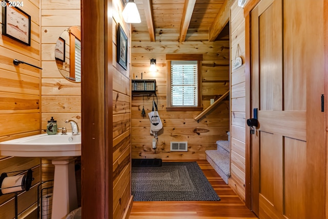 interior space with wooden walls, beamed ceiling, and hardwood / wood-style flooring