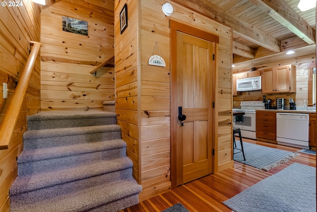 staircase with beam ceiling, wooden ceiling, wooden walls, and wood-type flooring