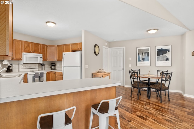 kitchen featuring sink, white appliances, kitchen peninsula, and a breakfast bar