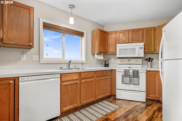 kitchen featuring decorative light fixtures, sink, white appliances, and dark wood-type flooring