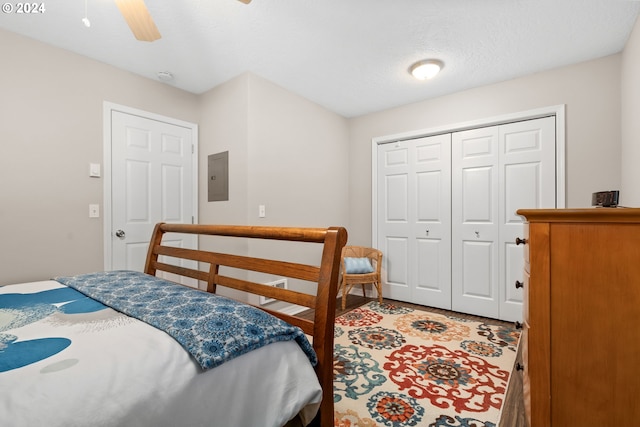 bedroom with electric panel, a textured ceiling, a closet, and ceiling fan