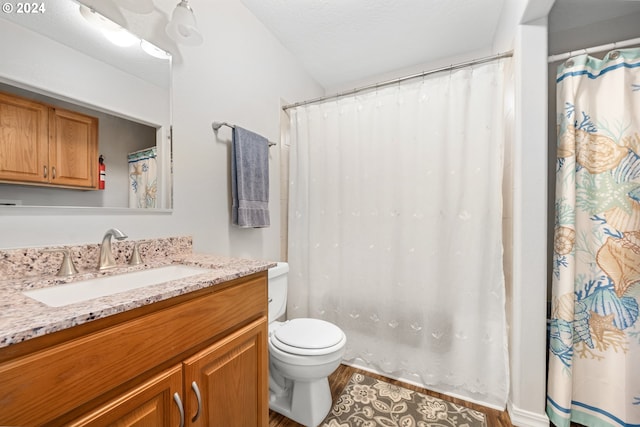 bathroom featuring toilet, a textured ceiling, hardwood / wood-style flooring, vanity, and lofted ceiling