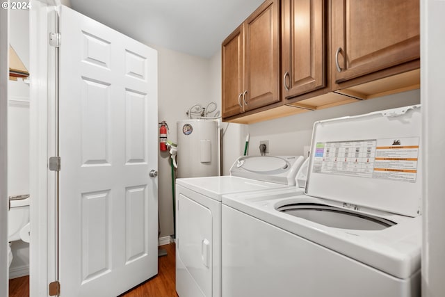 washroom featuring washer and dryer, light hardwood / wood-style flooring, cabinets, and water heater