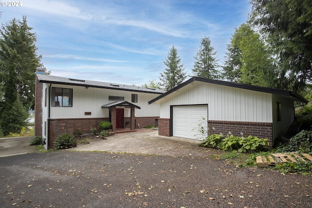 view of front of home with a garage, brick siding, and an outdoor structure