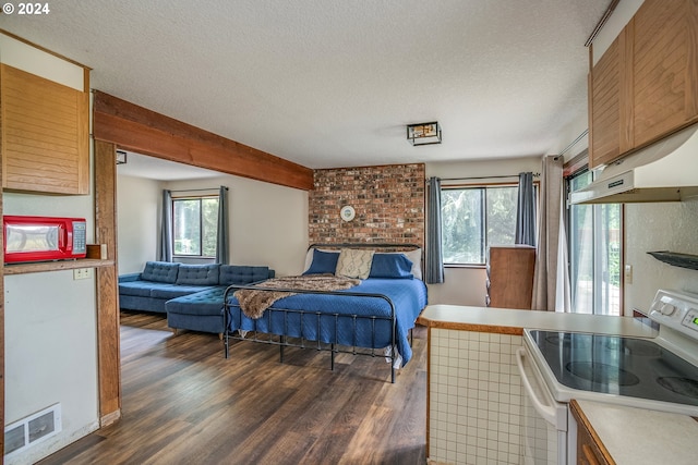 bedroom with a textured ceiling, beam ceiling, wood finished floors, and visible vents