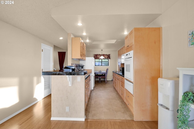 kitchen featuring light brown cabinets, a kitchen breakfast bar, white oven, light hardwood / wood-style flooring, and kitchen peninsula