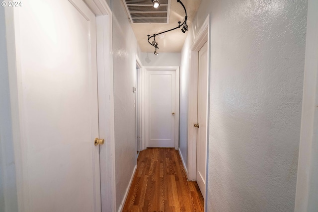 hall with rail lighting and hardwood / wood-style floors