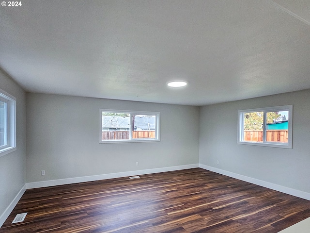 spare room featuring dark hardwood / wood-style floors and plenty of natural light