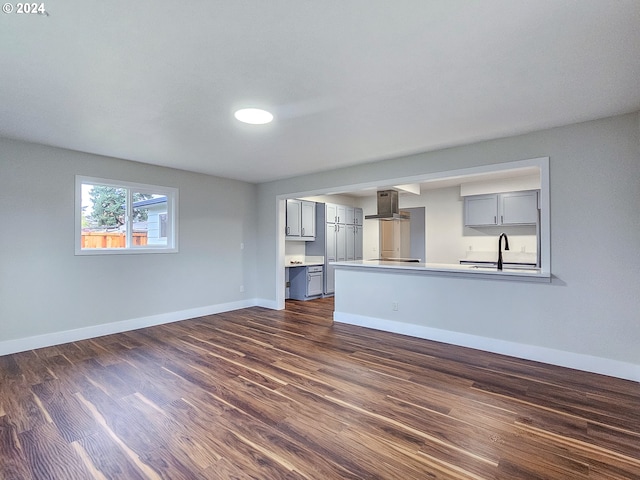 unfurnished living room featuring sink and dark wood-type flooring