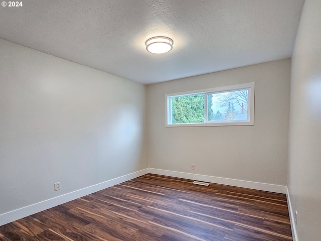 spare room featuring a textured ceiling and dark wood-type flooring