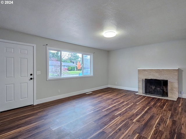 unfurnished living room with dark hardwood / wood-style floors, a fireplace, and a textured ceiling