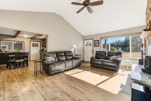 living room featuring a wood stove, high vaulted ceiling, light hardwood / wood-style floors, and ceiling fan