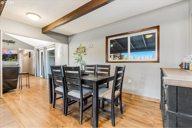 dining space featuring lofted ceiling with beams, a textured ceiling, and light hardwood / wood-style flooring