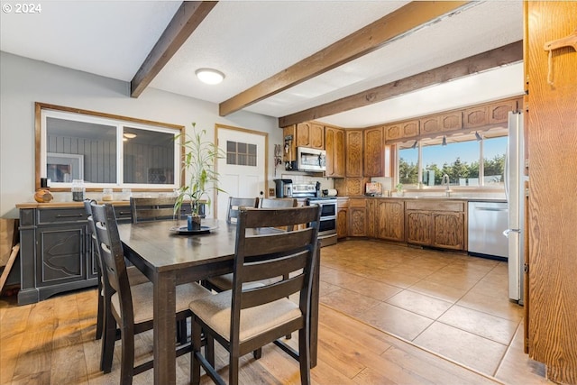 dining room with light hardwood / wood-style flooring, beamed ceiling, and sink