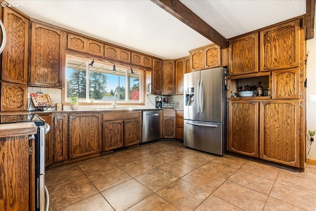 kitchen with beamed ceiling, decorative backsplash, light tile patterned flooring, and stainless steel appliances