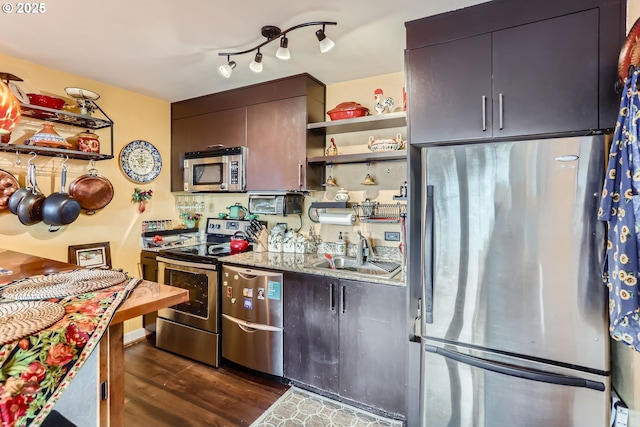 kitchen with dark wood-style floors, appliances with stainless steel finishes, light stone countertops, open shelves, and a sink