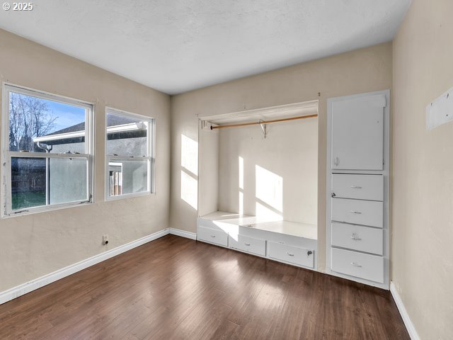 unfurnished bedroom with dark hardwood / wood-style floors and a closet