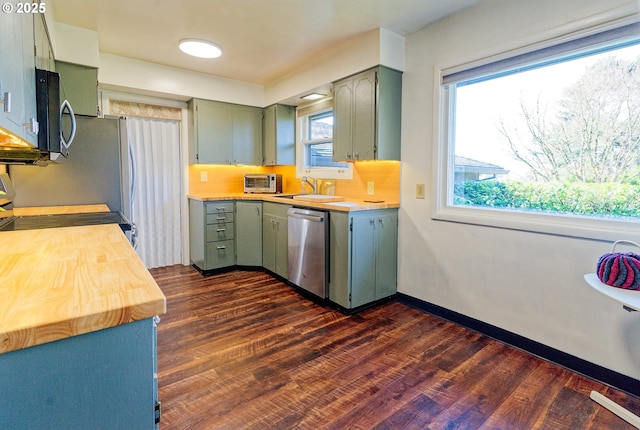 6312 SW Lesser Way, Portland, OR 97219 - kitchen with appliances with stainless steel finishes, green cabinets, dark wood-style flooring, and a sink