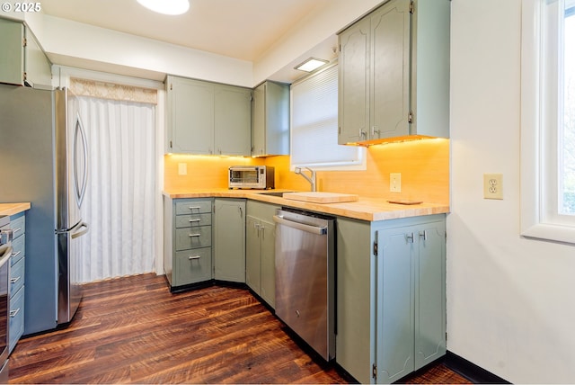 6312 SW Lesser Way, Portland, OR 97219 - kitchen with appliances with stainless steel finishes, dark wood-type flooring, backsplash, and a sink