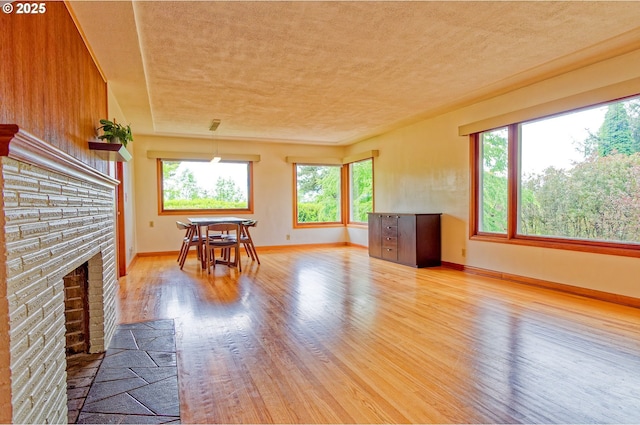 6312 SW Lesser Way, Portland, OR 97219 - dining room featuring light wood-type flooring, a fireplace with flush hearth, baseboards, and a textured ceiling