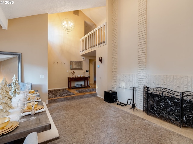 carpeted living room featuring a fireplace, high vaulted ceiling, and a chandelier